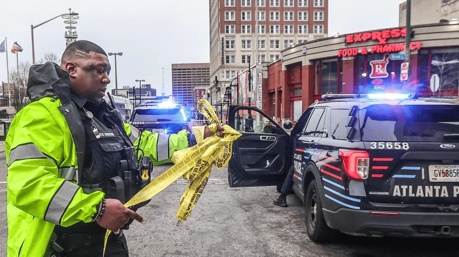Two American police officers secure an urban intersection with yellow crime-scene tape and patrol vehicles as new DOJ data show a 25% decline in serious violent victimization in 2025.
